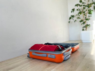 Turuncu seyahat valizini aç ve tahta zeminde gezmeye hazır ol.