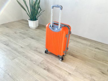 İçerde duran geniş saplı turuncu kabuklu bavul.