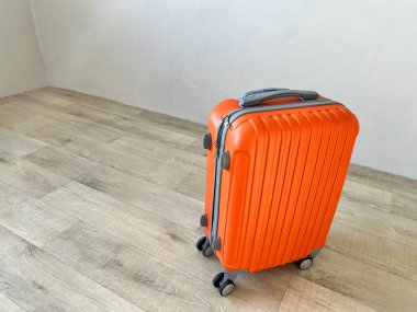 Turuncu bavul tatile hazır. Boş odadaki açık tahta zeminde.