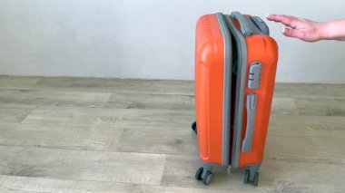 Bir kadın bavulu kapatmaya çalışıyor.