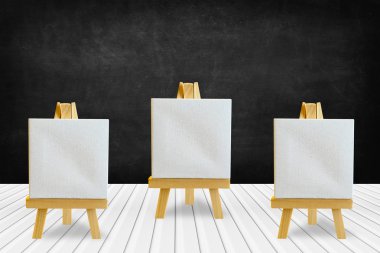 Tahta kaplamalı ahşap masa üstü ve boş bir tuvalle sehpa.