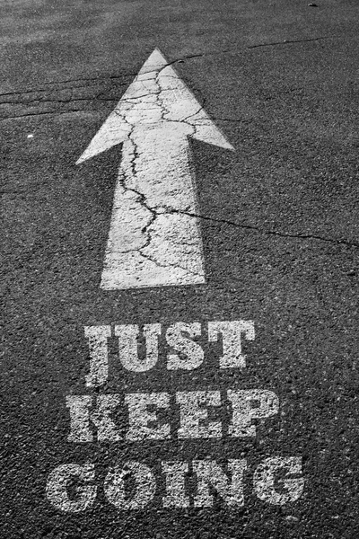 Arrow sign on asphalt surface with keep going word — Stock Photo, Image