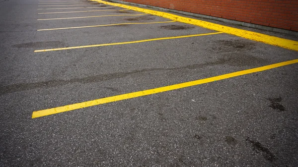 Um lugar de estacionamento vazio com linhas amarelas ao lado do edifício — Fotografia de Stock