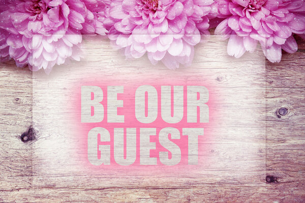pink flowers on wooden with word BE OUR GUEST