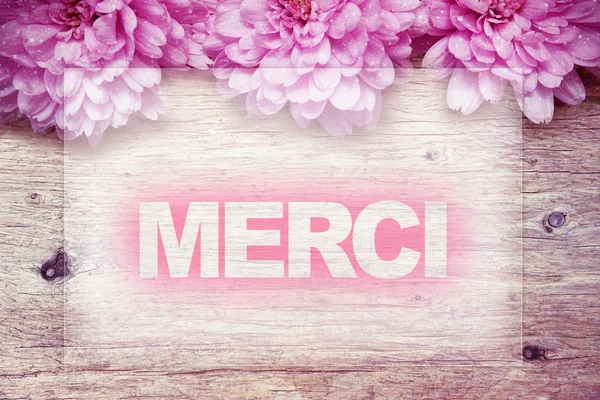Flores rosa em madeira com palavra Merci palavra francesa — Fotografia de Stock