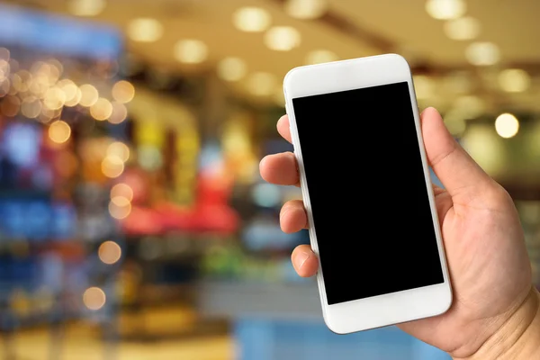 Vrouw hand met smartphone tegen vervagen bokeh van winkel backgro — Stockfoto