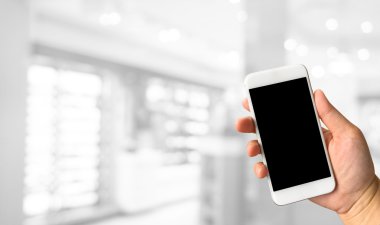 Kadın el smartphone beyaz gri bokeh soyut karşı tutarak 