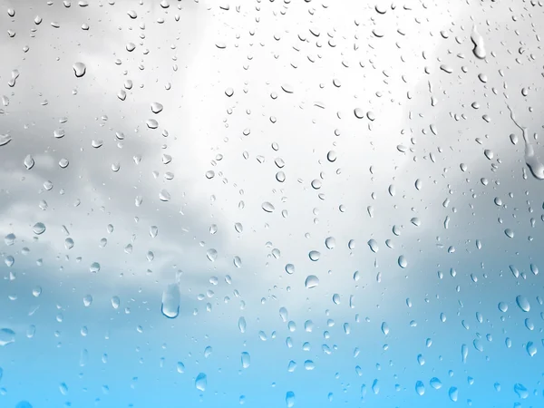 Gouttes de pluie sur fenêtre en verre, fond bleu gris ciel — Photo