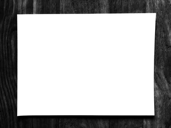 Простая белая бумага на размытом черном деревянном фоне — стоковое фото