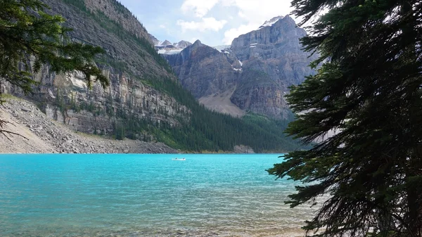 Beautiful lake, clearblue water with blur of people canoeing on — Stock Photo, Image