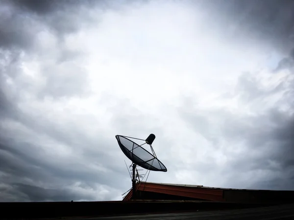 Satellit auf Dach vor wolkenverhangenem himmelgrauen Hintergrund — Stockfoto