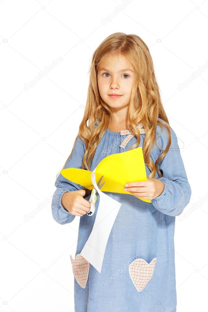 Cute little girl with scissors and yellow paper