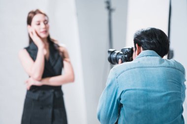 Profesyonel fotoğraf stüdyosu, Asyalı model aktris, makyöz ve fotoğrafçı ile birlikte, kamera arkasında, fotoğrafçılık endüstrisinde, profesyonel meslekte, beyaz arka planda bir portre.