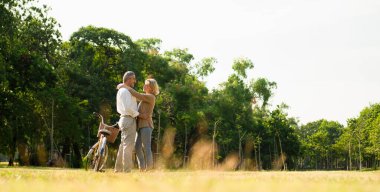 Kafkasyalı yaşlı çiftlerin doğal sonbahar güneşli bahçesinde bisikletin yanında durdukları ve birbirlerine baktıkları panoramik sevgi ve şefkat, yaşlı aşklar ve emeklilik hayatı..