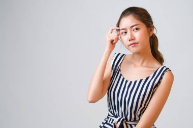 Çekici Asyalı genç bir kadının portresi düşünceli ve meraklı görünüyor. Gri arka planda fotokopi alanı solda, düşünceli kadın, meraklı düşünceli kadın..