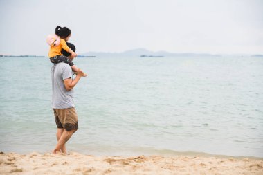 Baba, kızıyla birlikte kumsalda yürüyor. Hafta sonu birlikte vakit geçiriyor. Babalar günü konsepti, bekar baba konsepti..