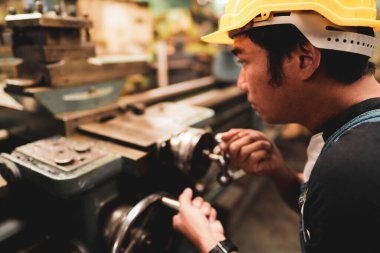 Asyalı bir endüstriyel işçi işletim makinesinin yan tarafı ve metal fabrikasında fotokopi alanı, imalat endüstrisi konsepti, kalifiye meslek mesleği ile sıcak bir tonda çalışmak..