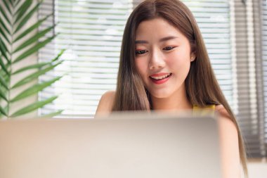 Bilgisayarla çalışırken gülümseyen Asyalı kadın.