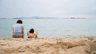 Baba ve kızı hafta sonu kumsalda birlikte vakit geçiriyorlar..