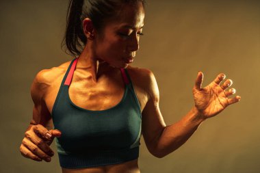 Kas kaslarının üst kısmını kapat. 40 yaşında sağlıklı vücut vücut geliştirme eğitimi almış Asyalı bir kadının vücut ısısı ve koyu arkaplandaki eğitimden sonra kas ve terini göster..