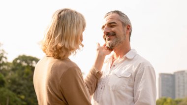 Son sınıf beyaz çiftin birbirlerine sarılıp mutlu oldukları öğleden sonra güneşi, yaşlı çiftin yıldönümleri, birliktelikleri, mutlu emeklilikleri, romantik çiftler, aşk ifadeleri.