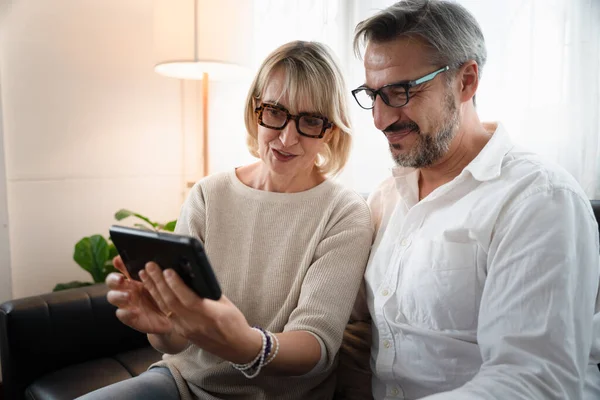 Happy couple elderly retirement using mobile phone to video conference call with family inthe living room atmosphere, Social distancing family during coronavirus pandemic.