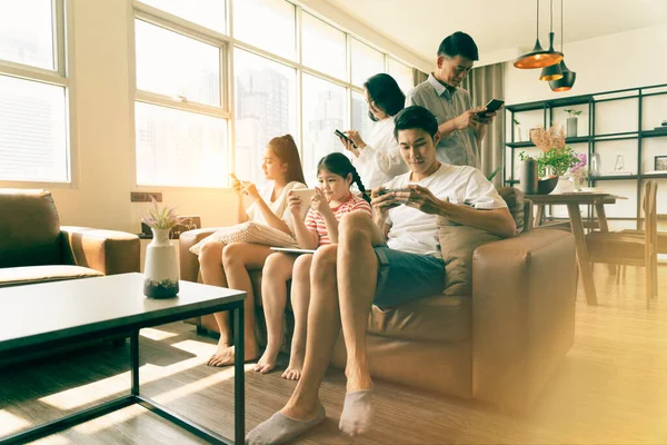 Social media addiction concept, Everyone in family using mobile phone in the living room. Problem of family relationships from mobile phone addiction.
