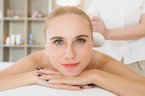 Close up of beautiful Caucasian woman lie down on her chest smiling and looking toward the camera in a spa atmosphere, feeling relax and comfortable, concept spa and beauty.