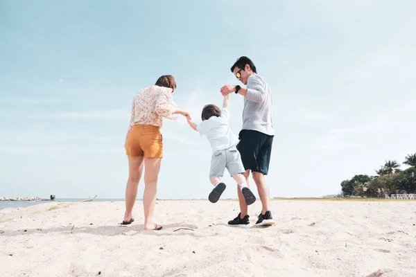 Back view of Asian happy family with a cute toddler having good time walking together on the tropical beach in the summer vacation, concept of family outing, Happytime of family on the beach.