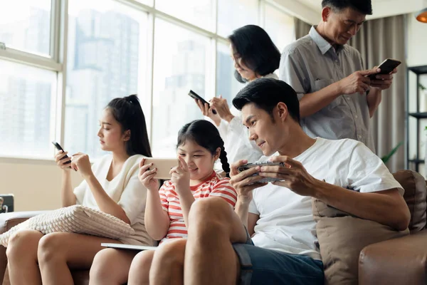 Fear of missing out, FOMO people. Social media addiction concept, Everyone in family using mobile phone in the living room. Problem of family relationships from mobile phone addiction.