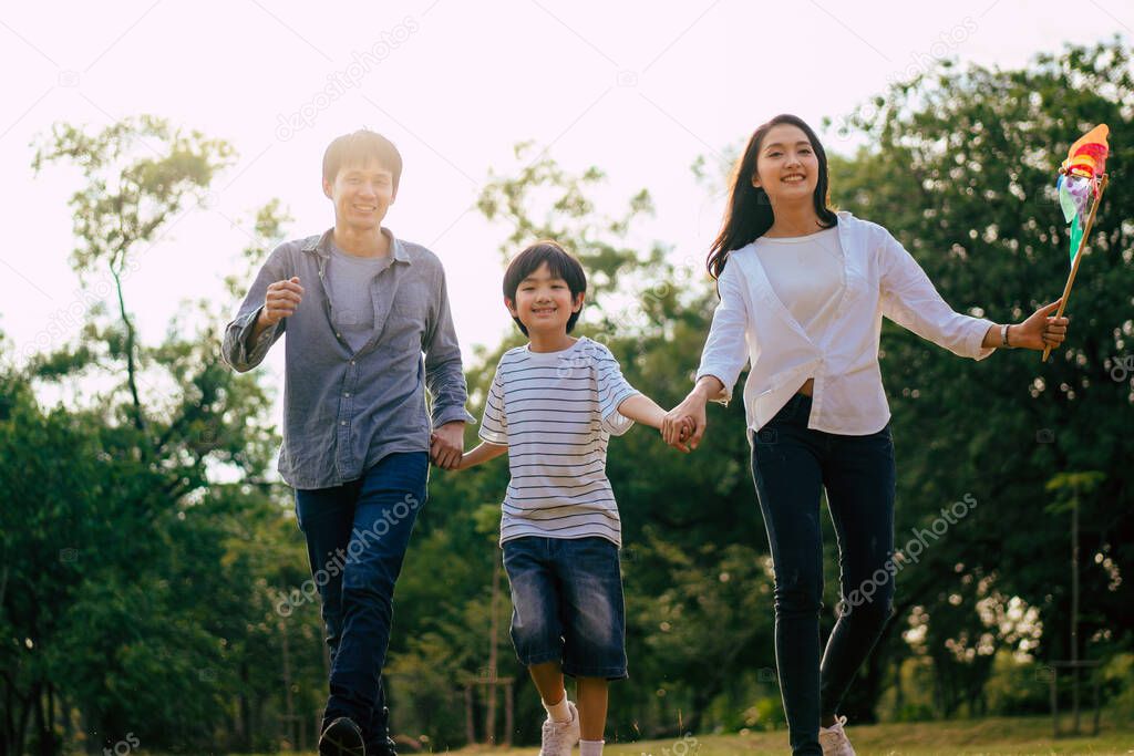 Scene of Asian happy family spend time together walking and relaxing at the park in the afternoon autumn, concept family togetherness, warm hearted family, parenthood, happy time family outing.