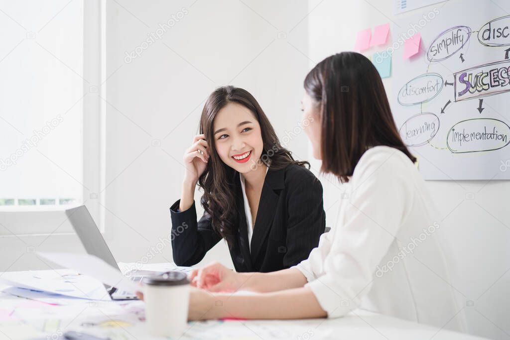 Scene of 2 beautiful asian business women talking and discussing happily in the white meeting room or office, happy working environment concept.