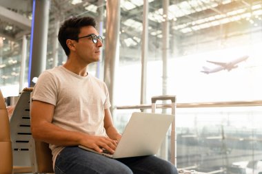 Bankta dizüstü bilgisayarı olan bir iş adamı uçağa binmek için beklerken havaalanından havalimanına bakıyor. Modern online iletişim teknolojisiyle çalışan akıllı cep telefonları.