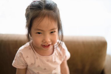 Asyalı küçük kız gülümseyecek ve haylaz, kendine güvenen, tatlı ve komik, çocuk gelişimi, erken çocukluk yaşam tarzı ile kameraya bakacak.