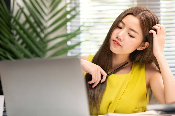 Genç Asyalı ofis kadını problemleri çözmeye odaklanıyor, masadaki bilgisayarına özenle bakıyor ve kafasını kaşıyor, konsept problemi çözümü, çalışan kadın yaşam tarzı, yeni bir iş kurma.