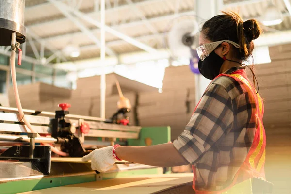 Fabrikada çalışırken yüz maskesi ve gözlük takan Asyalı bir fabrika işçisi. İş yerinde güvenlik kavramı.