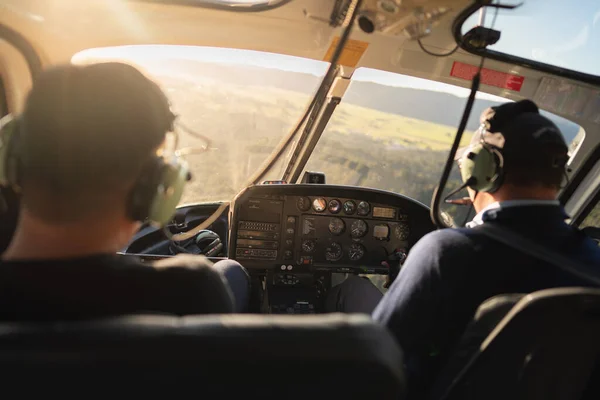 Arka koltukta iki pilotun bulunduğu helikopter kokpiti manzarası güneşli atmosferde helikopter turları yaparken, helikopter turları Yeni Zelanda 'daki en ünlü etkinliktir..