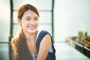 Elinde dostane bir gülümsemeyle not defteri tutan Asyalı genç bir kadının portresi. Güzel girişimci kız kameraya doğru bakarken sabah atmosferinde gülümsüyor..