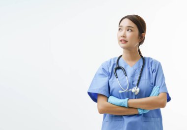 Asyalı doktor ya da eldiven takmış hemşire portresi kolunu çapraz yapıp doğru yöne bakıyor ve beyaz arka planda fotokopi alanı ile duruyor. Sağlık hizmetleri kahramanı kavramı.