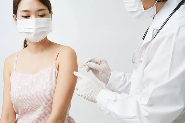 専門医や看護師は 保護面マスクの患者女性の注射器ワクチンを使用します 予防接種や予防接種キャンペーン中に病院や保健センターでワクチンを取得アジアの女の子 — ストック写真