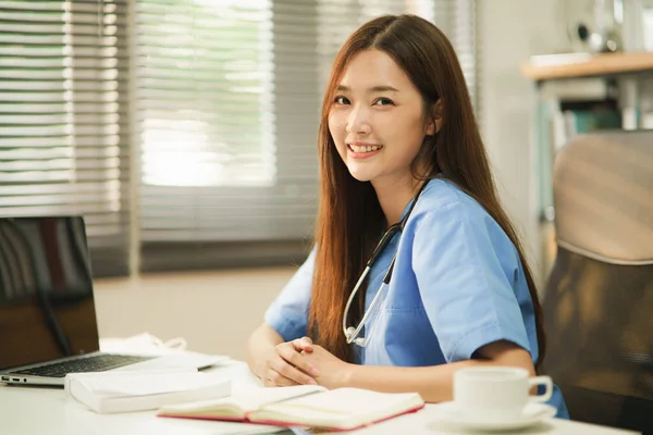 中等特写的亚洲女医生或护士的肖像 听诊器微笑着坐在房间里拍照 乐观的医务人员在值班 医疗幸福的写照 — 图库照片