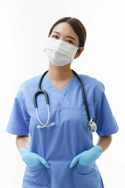 白い背景の上に笑顔聴診器で保護顔マスクと亜硝酸手袋を身に着けている若いアジアの専門看護師の女性の垂直肖像画 — ストック写真