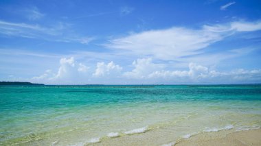 Denizin dalgası kumsalda, parlak mavi gökyüzü