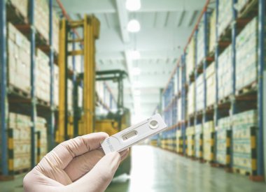 Eldivenli el, COVID-19 hızlı testi. Arka planda bulanık giysi sonucu negatif çıktı. Çalışma alanına girmeden önce antijen çubuk tespiti..