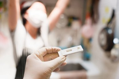 Negatif COVID-19 'u tutan lastik eldiven giyen bir el arka planda mutlu görünen bulanık insanlarla sonuçlanır. Evde SARS-CoV-2 Ag antijen testi, hızlı antikor muayenesi.