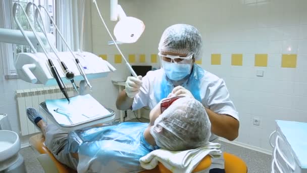 Врач и его ассистент лечат пациента в стоматологии — стоковое видео