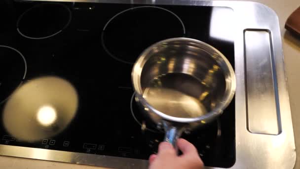 Mans main met et tord une casserole sur un poêle électrique au ralenti Vidéo De Stock