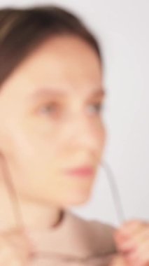 Gözlüklerini çıkarıp yorgun gözlerini ovuşturan, tanınmayan bir kadının dikey odaklanma görüntüsü. Bulanık görme, göz yorgunluğu ve düzeltme ihtiyacı kavramı.