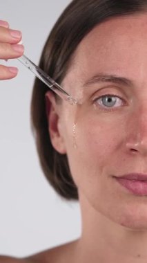 Yüz serumu süren sakin bir kadının yüz yağını yakından çek. Cilt bakımı ve güzellik tedavisi. Dikey ekran