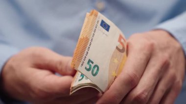 50 avroluk banknotları sayarak erkek eli çekiyoruz. Mavi gömlekli adam para sayıyor, Avrupa parası. Maaş, tasarruf veya bütçe planlaması için mali konsept